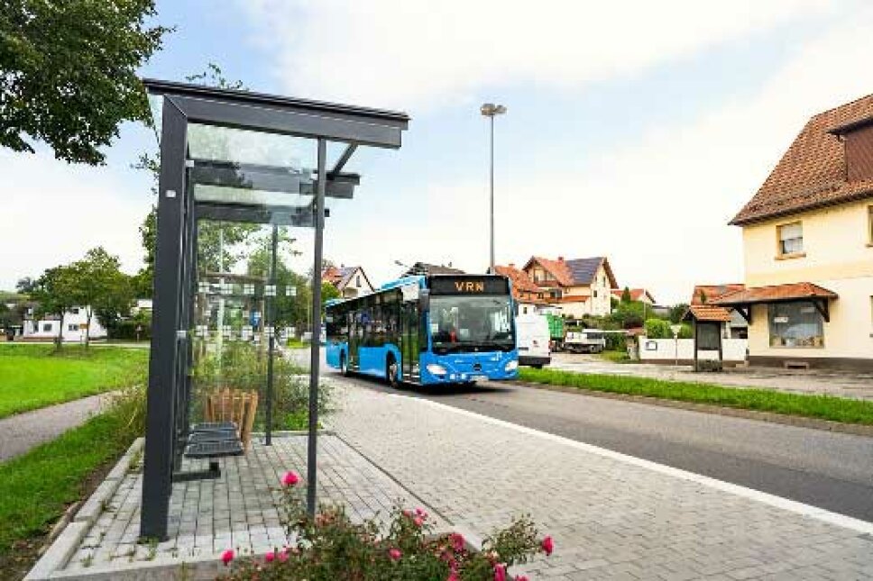 ein blauer Bus fährt an eine Bushaltestelle