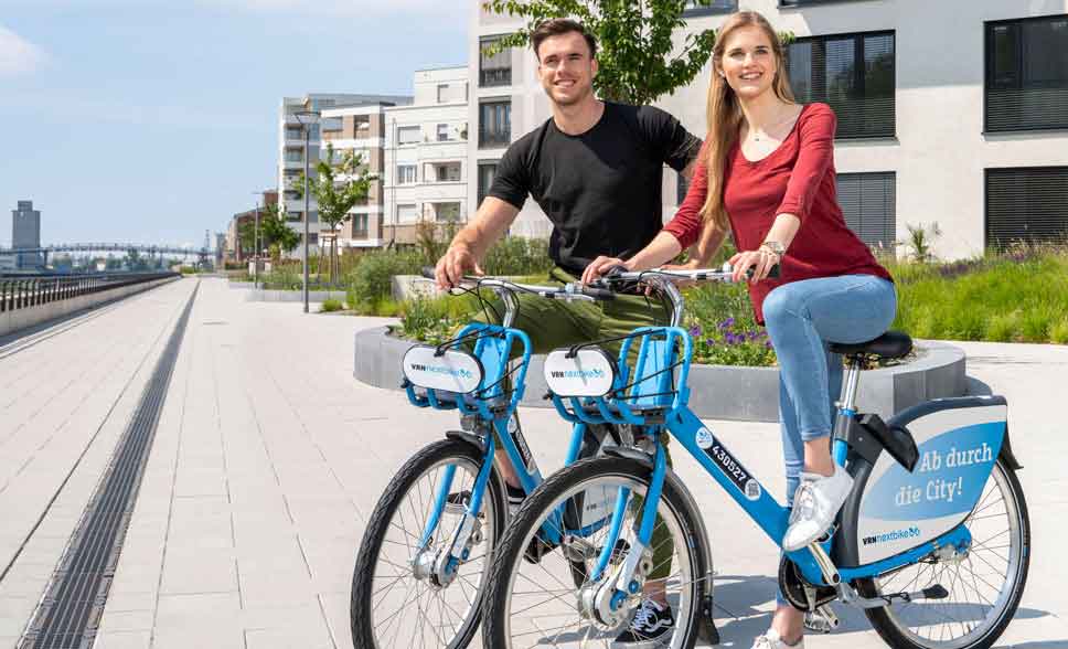 Junge Frau und junger Mann mit nextbike-Rädern vor einem Gebäude